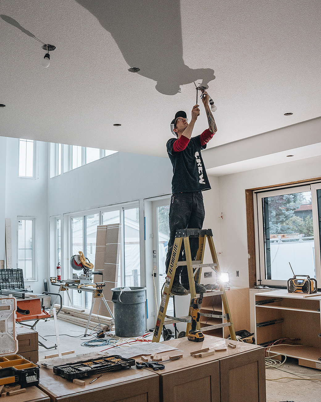 A professional electrician in Auburn Bay installs a new light in a modern dining room.