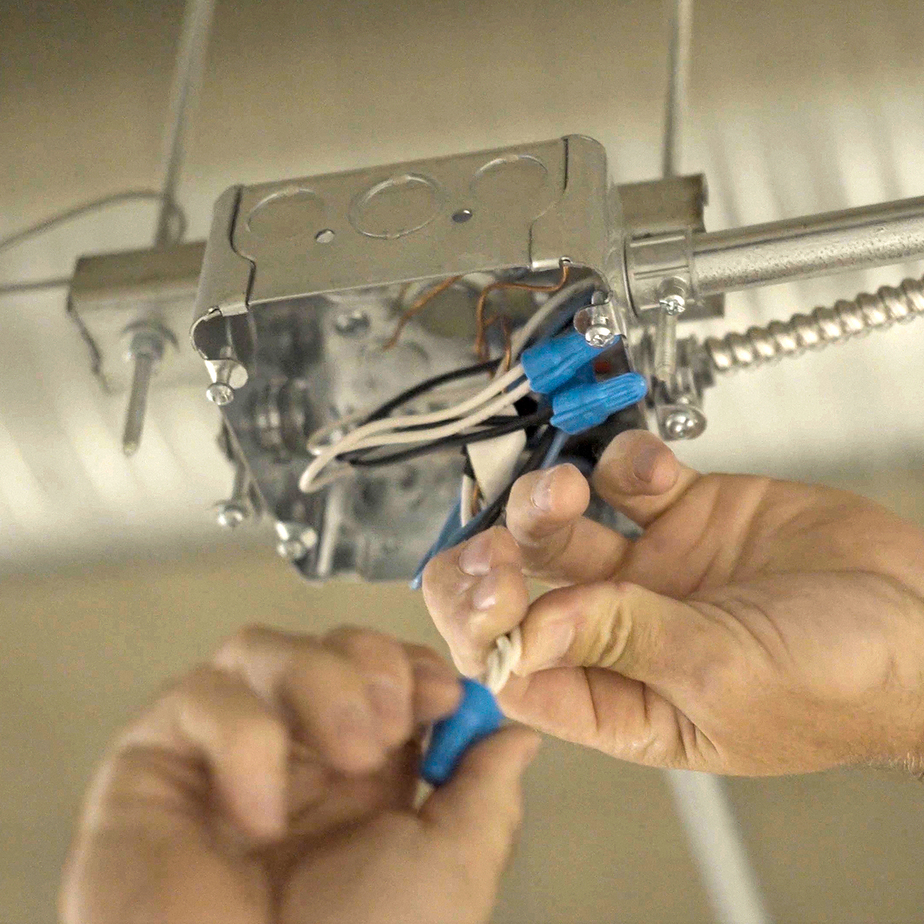 Crew Technical Services electrician mounting a ceiling fan in a Calgary bedroom